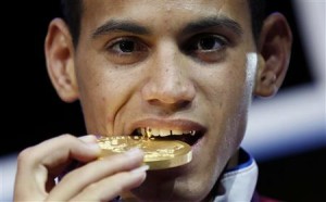 Gold medallist Robeisy Ramirez Carrazana of Cuba bites his medal during the presentation ceremony for the Men's Fly (52kg) boxing competition at the London Olympics