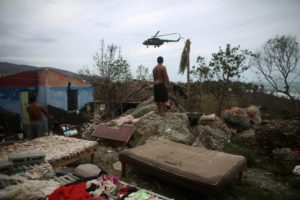 A man watches an army helicopter flying over his damaged home in Cajobabo after the passage of Hurricane Matthew.  REUTERS/Alexandre Meneghini