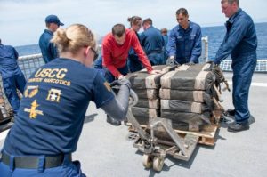 In this July 19, 2015 photo released by the U.S. Coast Guard, crew members secure cocaine bales from a self-propelled semi-submersible interdicted in international waters. Officials say drug traffickers are increasingly turning to the sea to get their loads to U.S. markets.