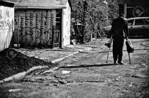 9489303-Un-pobre-hombre-enfermo-con-muletas-caminando-por-la-calle-Vista-posterior-blanco-y-negro-Foto-de-archivo