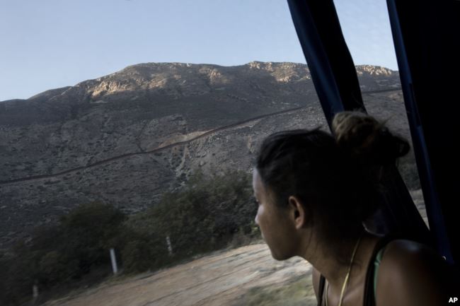 Un migrante centroamericano mira hacia la frontera con los Estados Unidos, entre Mexicali y Tijuana, mientras viaja en autobús con una caravana de migrantes a Tijuana, México, el 26 de abril de 2018.