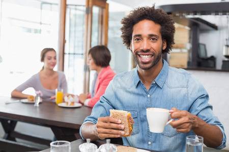 31347689-handsome-man-eating-a-sandwich-at-the-coffee-shop